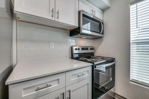 a kitchen with white cabinets and a stove and a microwave